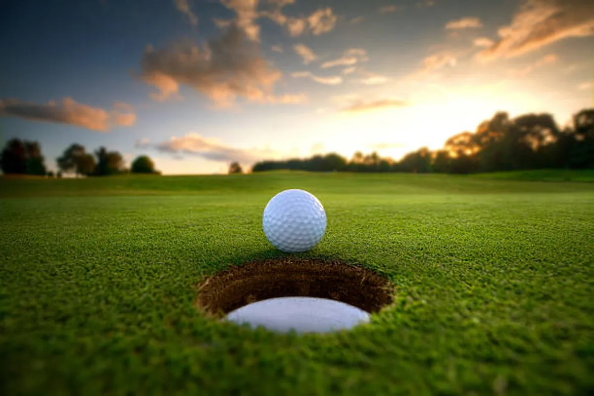 A close-up shot of a golf ball perched right next to the hole on a lush green fairway, with well-manicured grass and soft natural lighting. This image visually emphasizes the golfing experience, inviting viewers to imagine themselves in the moment of a perfect putt.