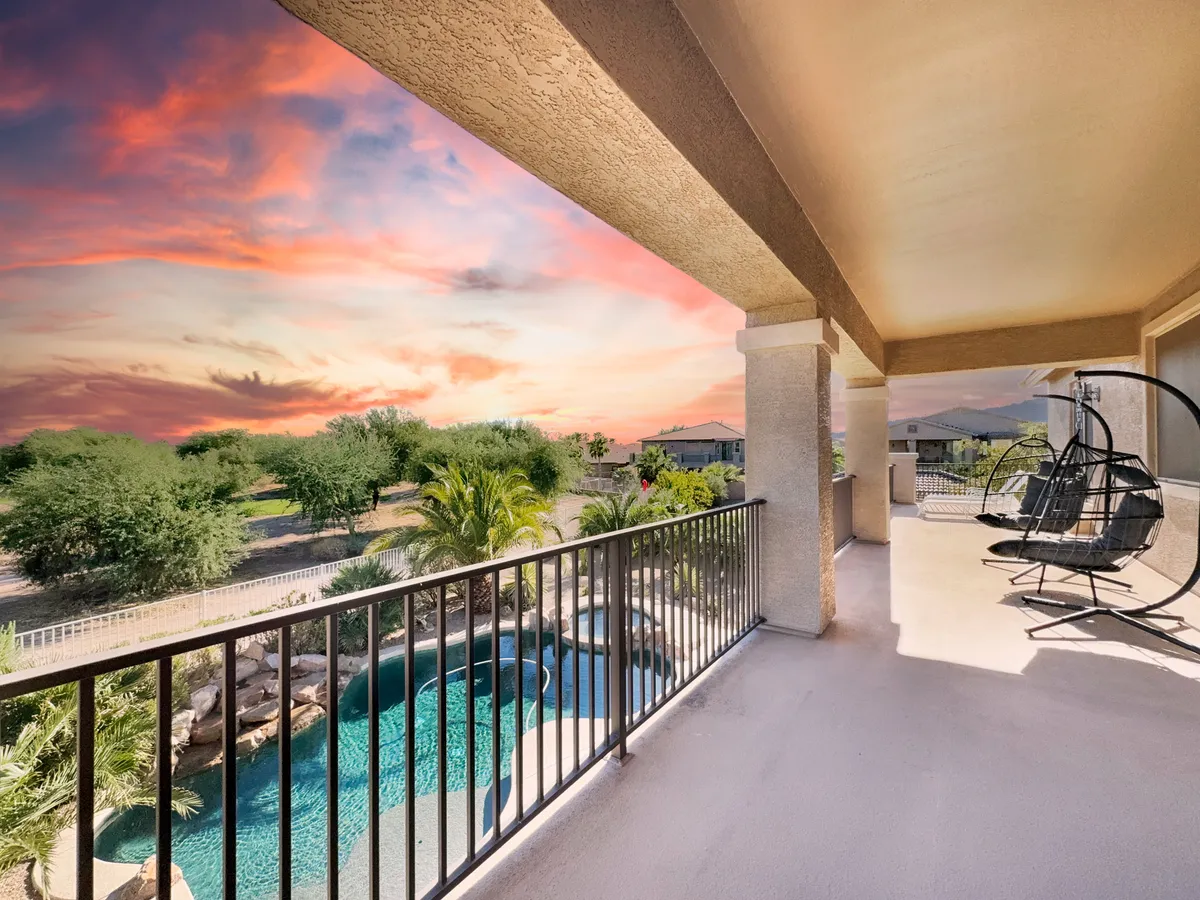 A serene balcony scene with a swimming pool, a hanging chair, landscaped gardens, and a glowing sunset sky. The inviting setup captures the peacefulness and luxury of the outdoor leisure spaces.