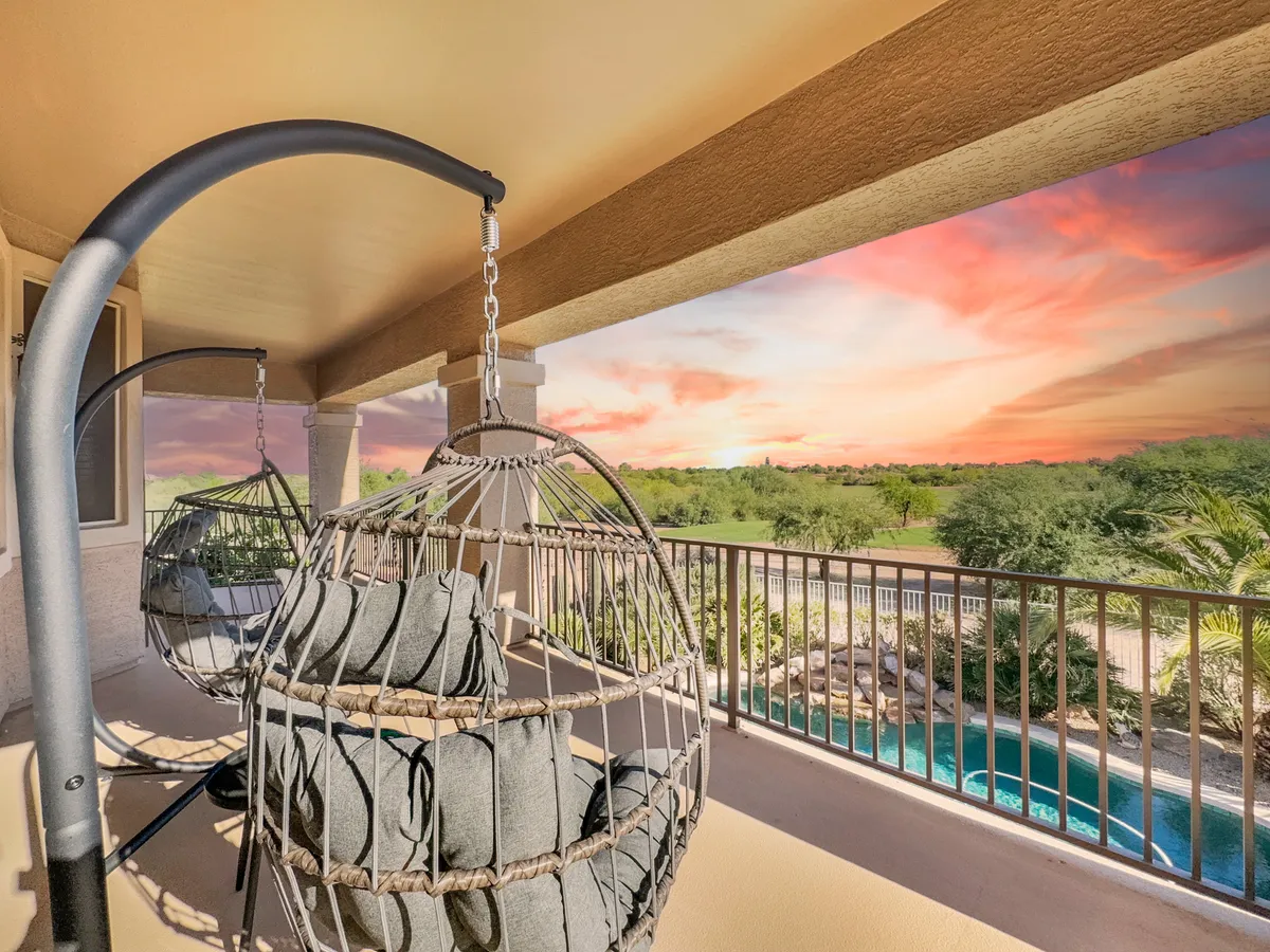 An inviting exterior view featuring cozy hanging chairs, a tranquil pool area, and a stunning sunset in the background. The scene suggests relaxation and social opportunities after a day on the course.